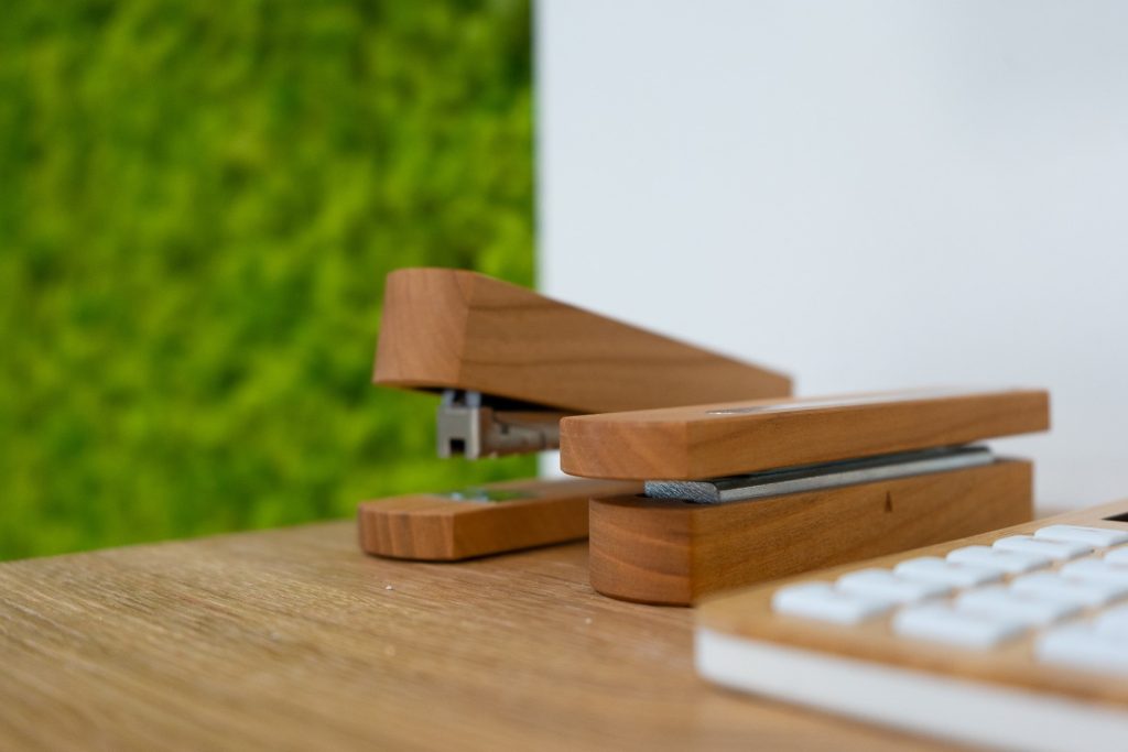 Ein Tacker, ein Stempel und ein Taschenrechner aus Holz liegen auf einem Tisch.